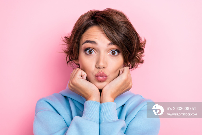 Closeup photo of young gorgeous nice pretty woman wear blue sweater touch cheeks hands air kiss pouted lips flirty isolated on pink color background