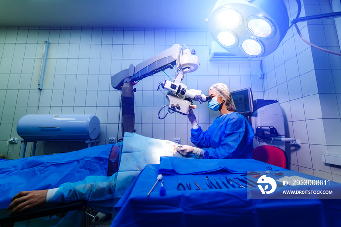 Surgeon looking into the microscope at the eye of a patient at the operating room. Modern equipment. Vision correction