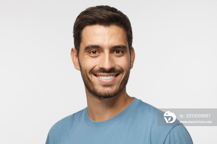 Smiling attractive man in blue t-shirt isolated on gray background