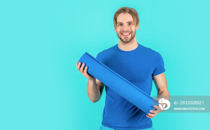 sport man with yoga mat isolated on blue background with copy space. sport man with yoga mat