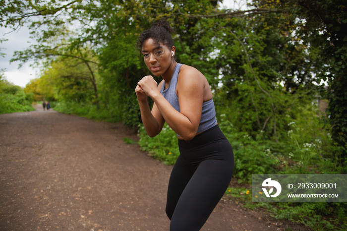 Young curvy woman with vitiligo working out in the park  with earbuds and looking fierce