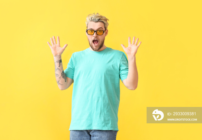 Surprised young man with stylish sunglasses on color background