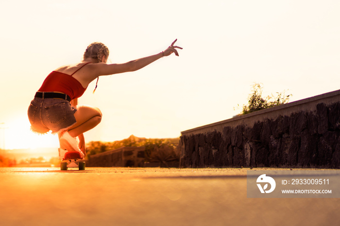 Beautiful young girl on his longboard on the road in the city in sunset day. Extreme sports, rear view of motion. Copy space. Lifestyle and sport concept.