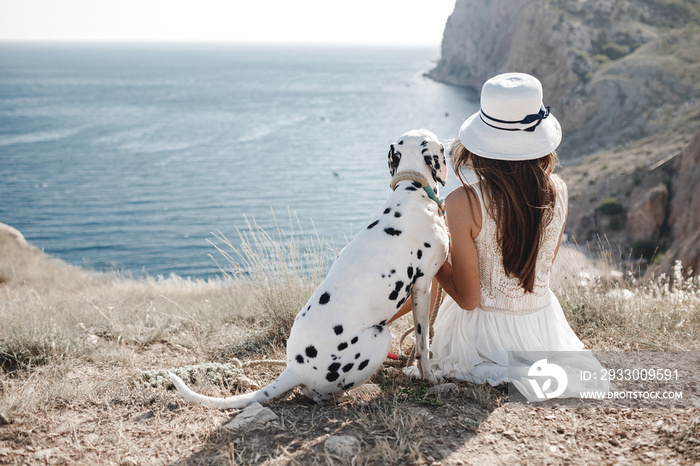 Happy woman with a dog dalmatian near the beach, backside