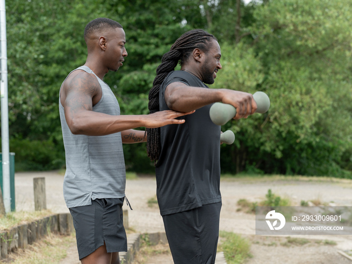 Two men exercising with dumbbells in park