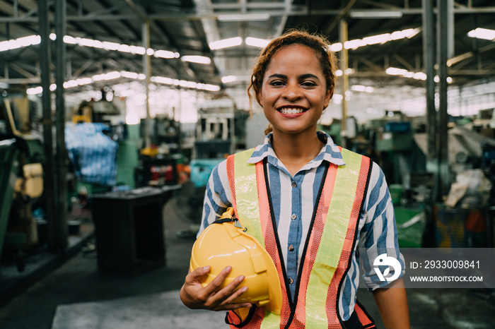 attractive young african woman smiling and working engineering in industry.Portrait of young female worker in the factory.Work at the Heavy Industry Manufacturing Facility concept.