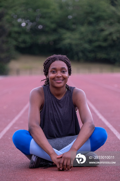 Portrait of smiling athletic�woman sitting on running track