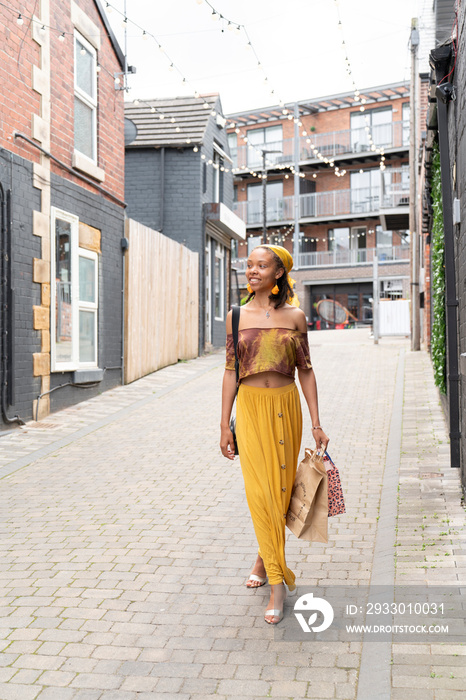 Young woman walking with shopping bags in city