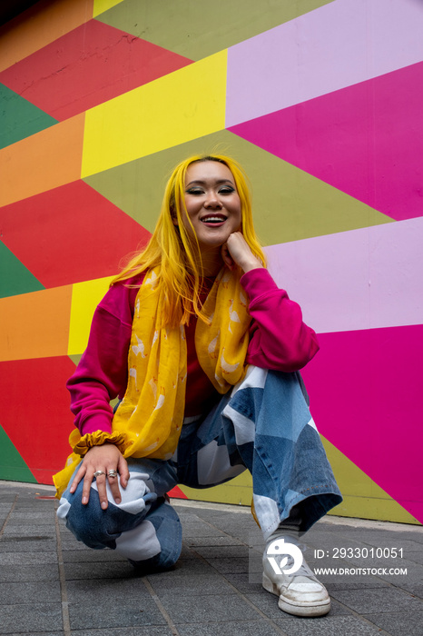 Portrait of young woman with yellow hair crouching outdoors