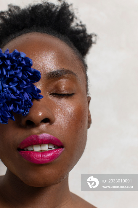 Woman with closed eyes, holding flower in front face