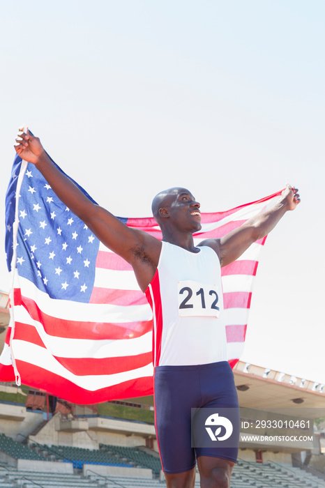 Happy male track and field athlete celebrating with American flag