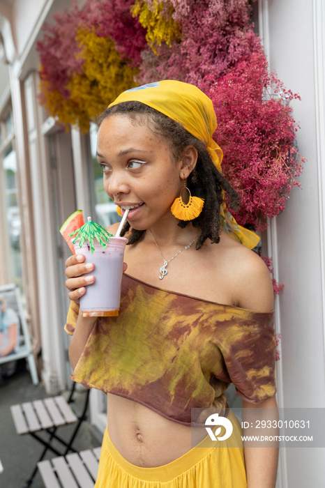 Portrait of young woman drinking smoothie in city