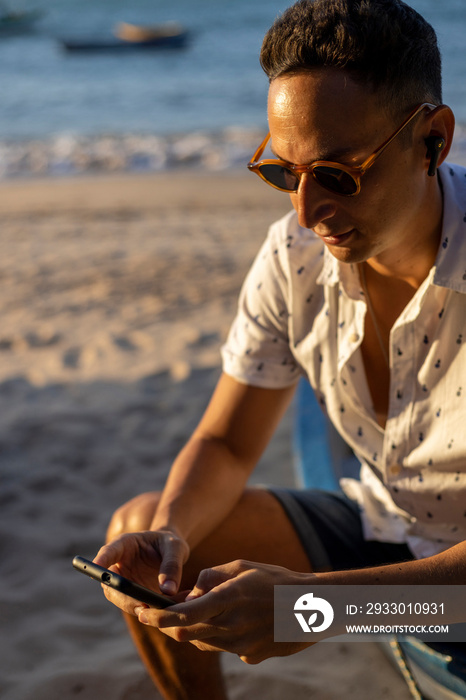 Man sitting at beach and using smart phone