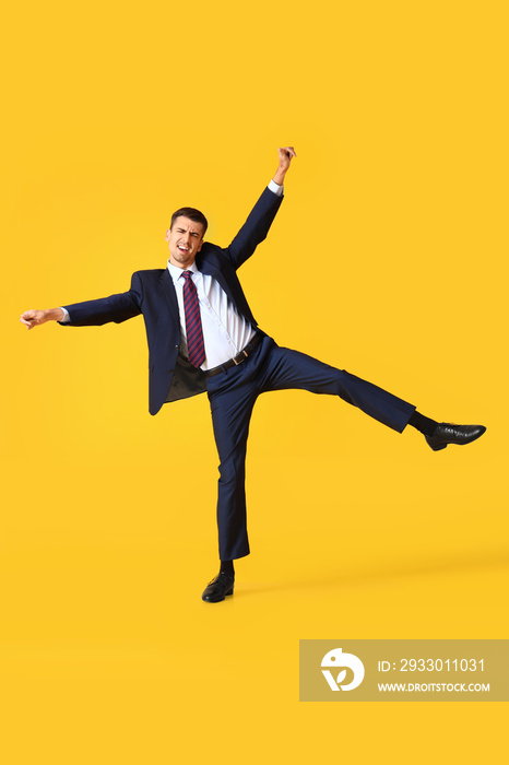 Dancing young businessman on yellow background