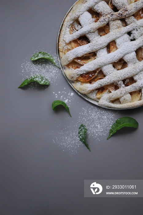 Apple pie on grey background. Dessert. Homemade cake. Autumn flatlay. Homemade piece of cake with mint and sugar powder.