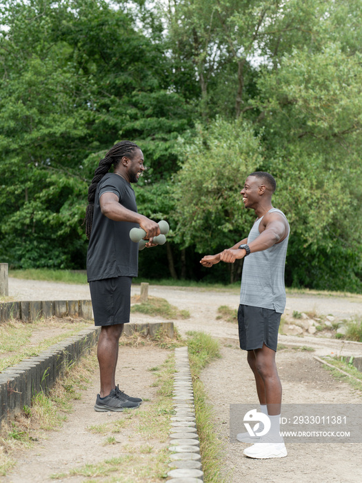 Two men exercising with dumbbells in park