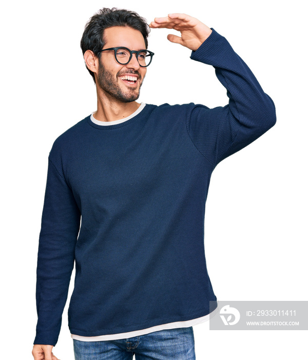 Young hispanic man wearing casual clothes and glasses very happy and smiling looking far away with hand over head. searching concept.