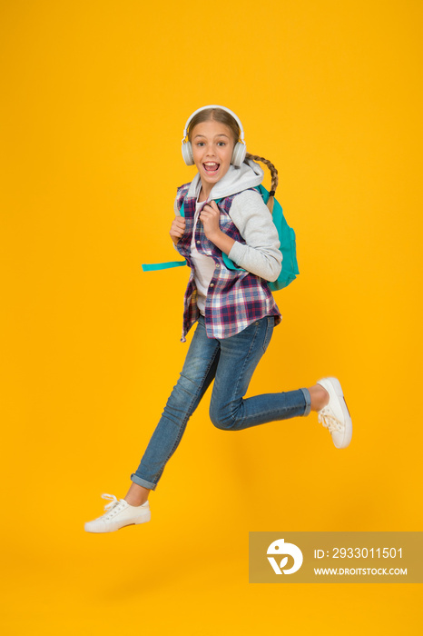 Song of happiness. Active girl jump with happiness yellow background. Happy child enjoy music playing in headphones. Happiness frequency. Music for happiness and positive thinking. Back to school