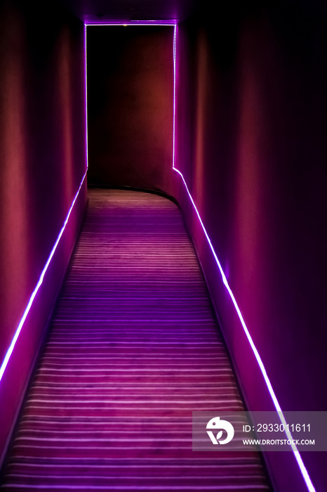 Dark passageway with purple neon strip lights at entrance to nightclub