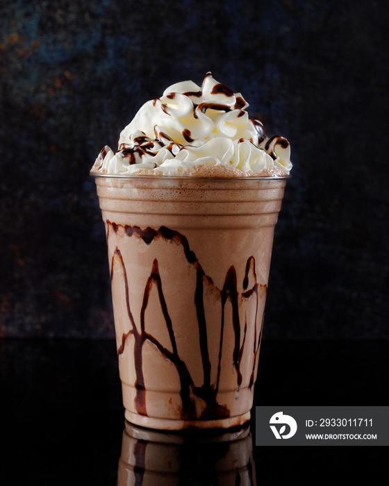 Chocolate milkshake served in a clear glass on a dark background. Isolated drink.