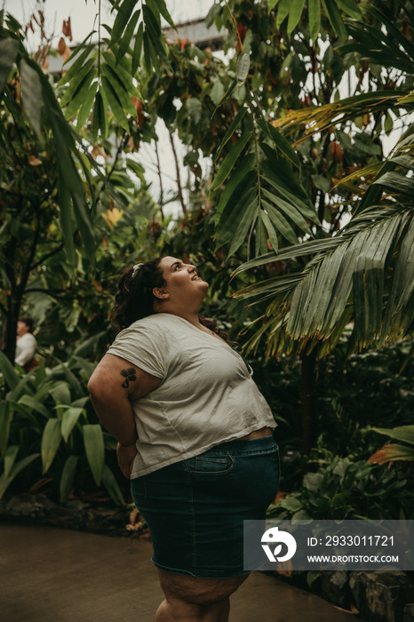 plus size woman looks up at tropical plants