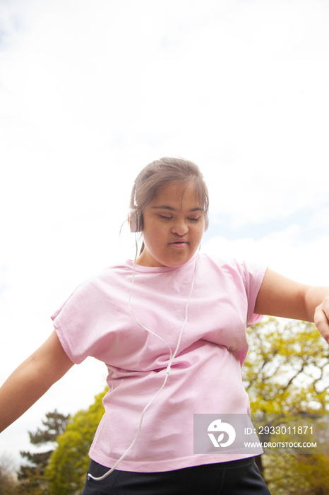 Young mid-sized woman with Down syndrome dancing outdoors