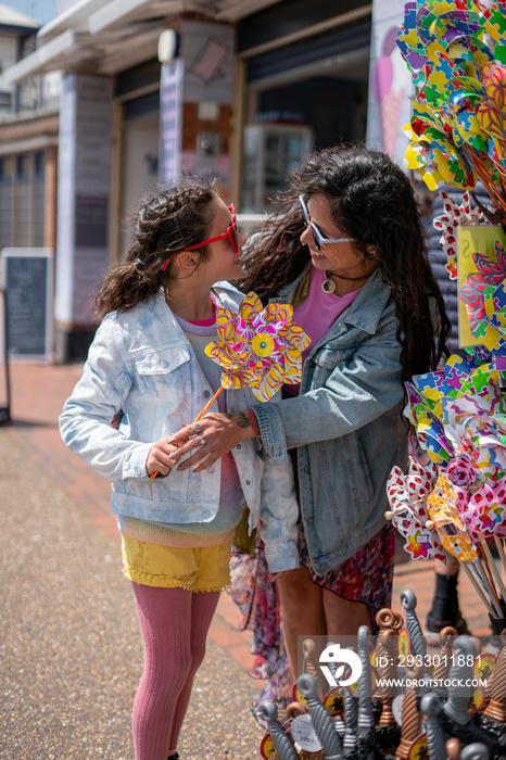 Smiling mother and daughter (8-9) buying pinwheel at street stand