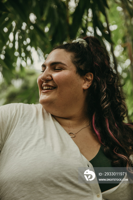 closeup of plus size woman smiling with eyes closed surrounded by plants