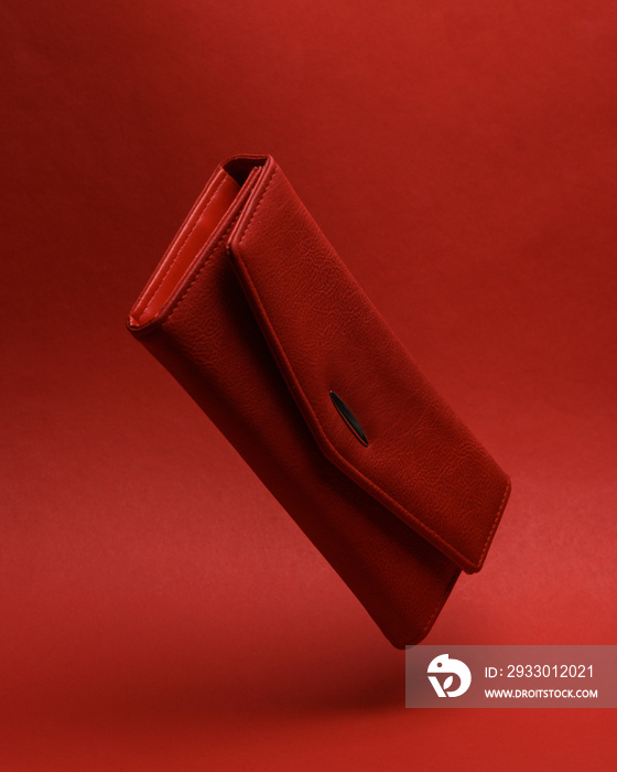 Red leather wallet Levitating in the air or hovering on red background with shadow. Minimal fashion concept