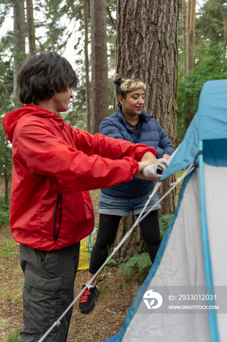 Mother and son setting up tent in forest