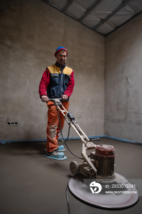 worker performing and polishing sand and cement screed floor