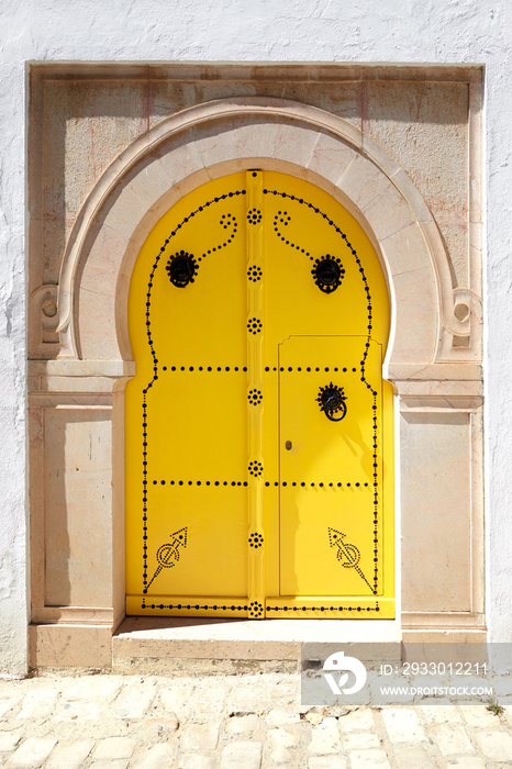 Vintage yellow door in Arabic style with a metal ornament.