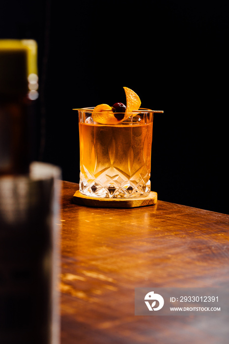 old fashioned cocktail glass between bottles in a bar