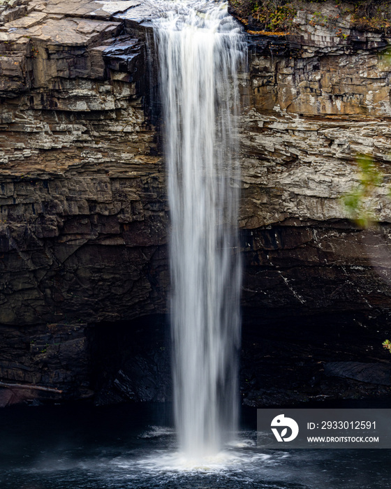 high waterfall falling down rock face into large pool below