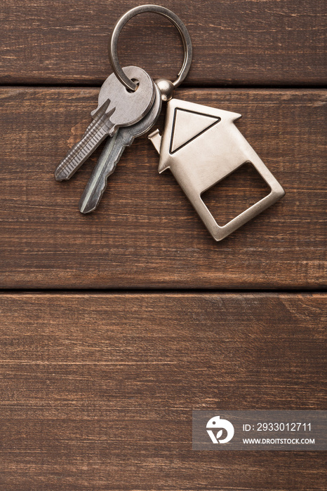 Bunch of keys with house shaped keychain on brown wood