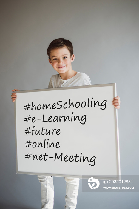 boy holding white sign with the words homeschooling and more during corona crisis