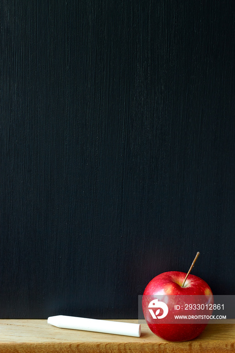 Back to school concept, close-up of a clean black chalk board, white chalk and red apple, selective focus, copy space