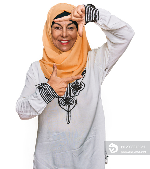 Middle age hispanic woman wearing traditional islamic hijab scarf smiling making frame with hands and fingers with happy face. creativity and photography concept.