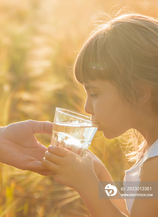 The father gives the child a glass of water. Selective focus.