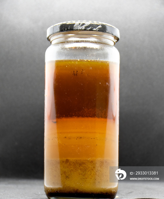 Layers of cooking Fat Oil and Grease in a glass jar. On a black background