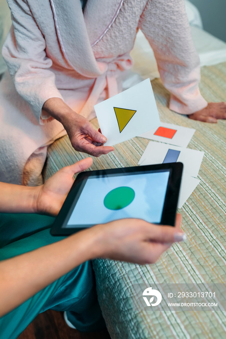 Female doctor showing geometric shape game to elderly female patient with dementia