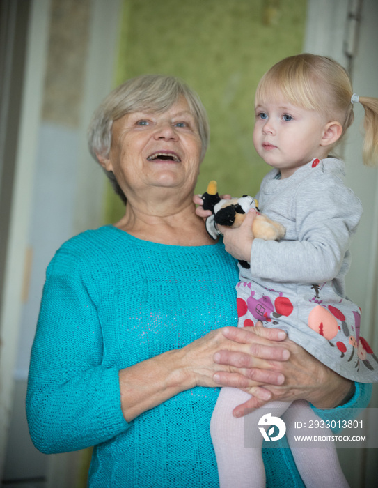 A smiling grandmother holding a little baby girl