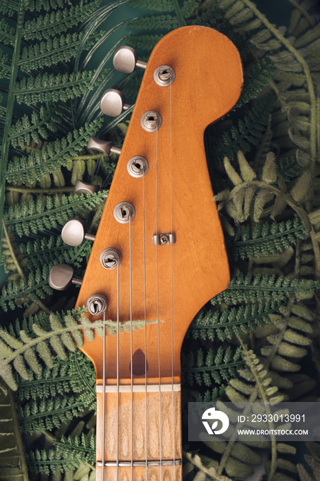 Jungle plants surrounding electric guitar headstock. Nature and technology concept.