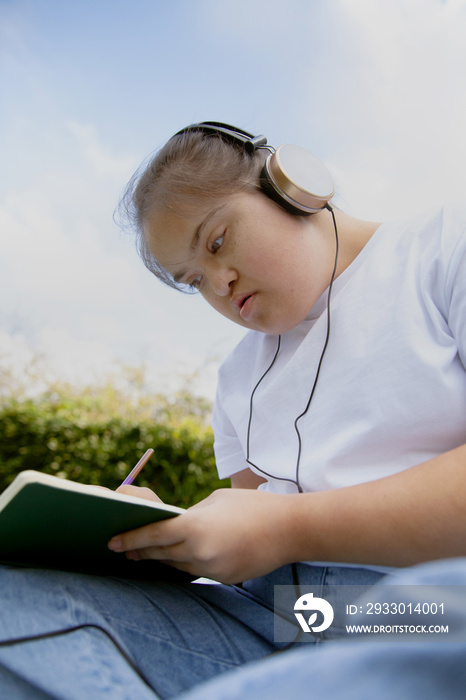 Young mid-sized woman with Down Syndrome listening to music in the park