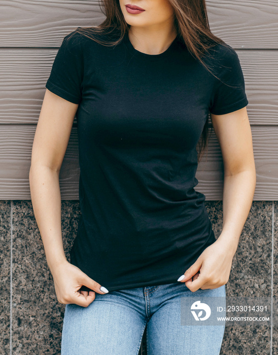 Stylish brunette girl wearing black t-shirt posing against street , urban clothing style. Street photography