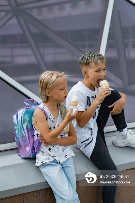 Two happy children, brother and sister, sibling interaction. Brother and sister dressed in casual eating ice cream in a cone.