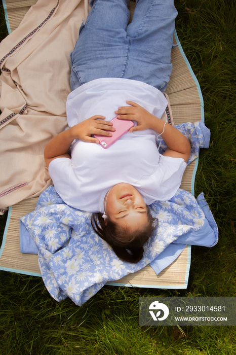 Curvy girl with Down syndrome listening to music in the park