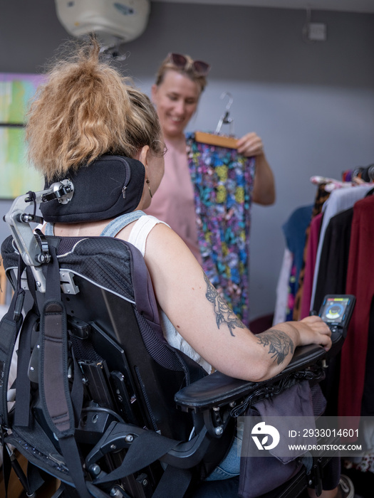 Assistant helping woman in wheelchair pick clothes