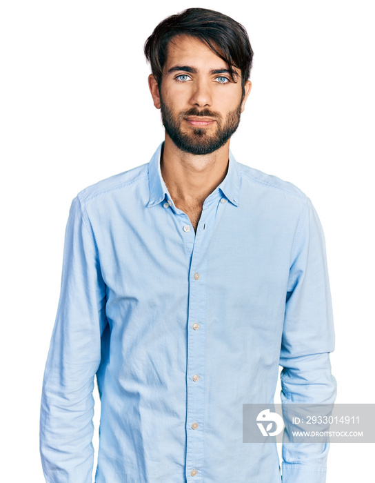 Hispanic man with blue eyes wearing business shirt relaxed with serious expression on face. simple and natural looking at the camera.