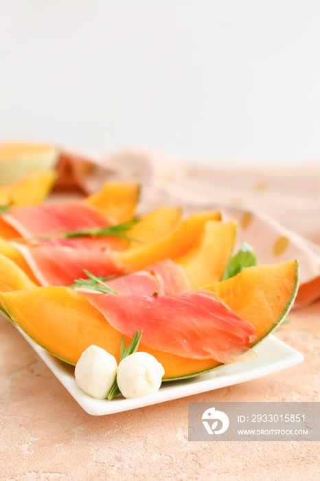 Plate with delicious melon, mozzarella and prosciutto on color background